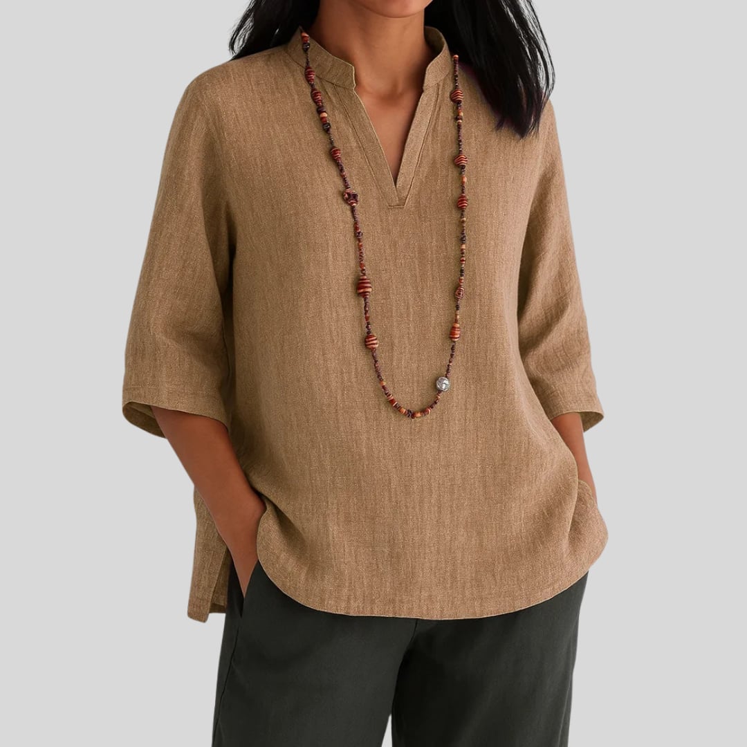 Front view of the Claudia blouse in green, draped elegantly and paired with casual bottoms