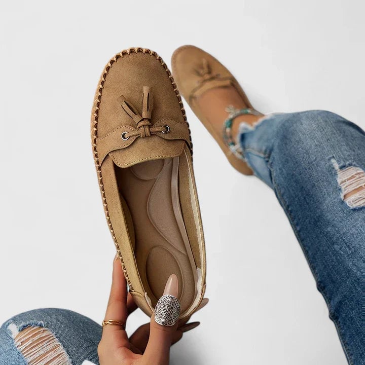 Close-up of the moccasin stitched edge and bow accent on Clea suede flats in caramel brown