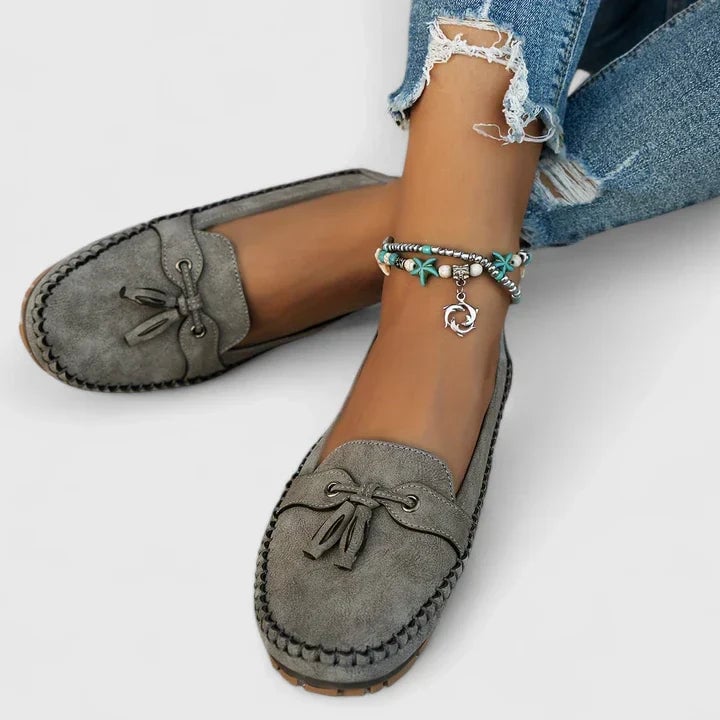 Clea grey suede loafers styled with white jeans and a linen top on a light background