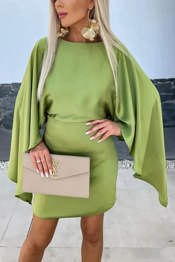 Woman wearing the Cleo sage green cape sleeve bodycon mini dress with dramatic batwing sleeves, front view