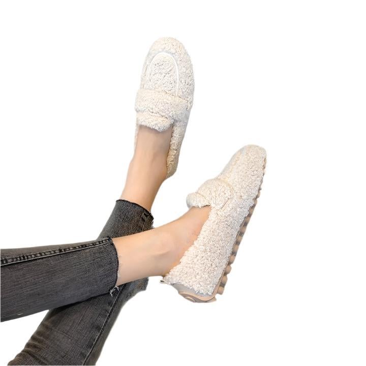 Woman wearing cream plush moccasin slippers on a cozy indoor floor