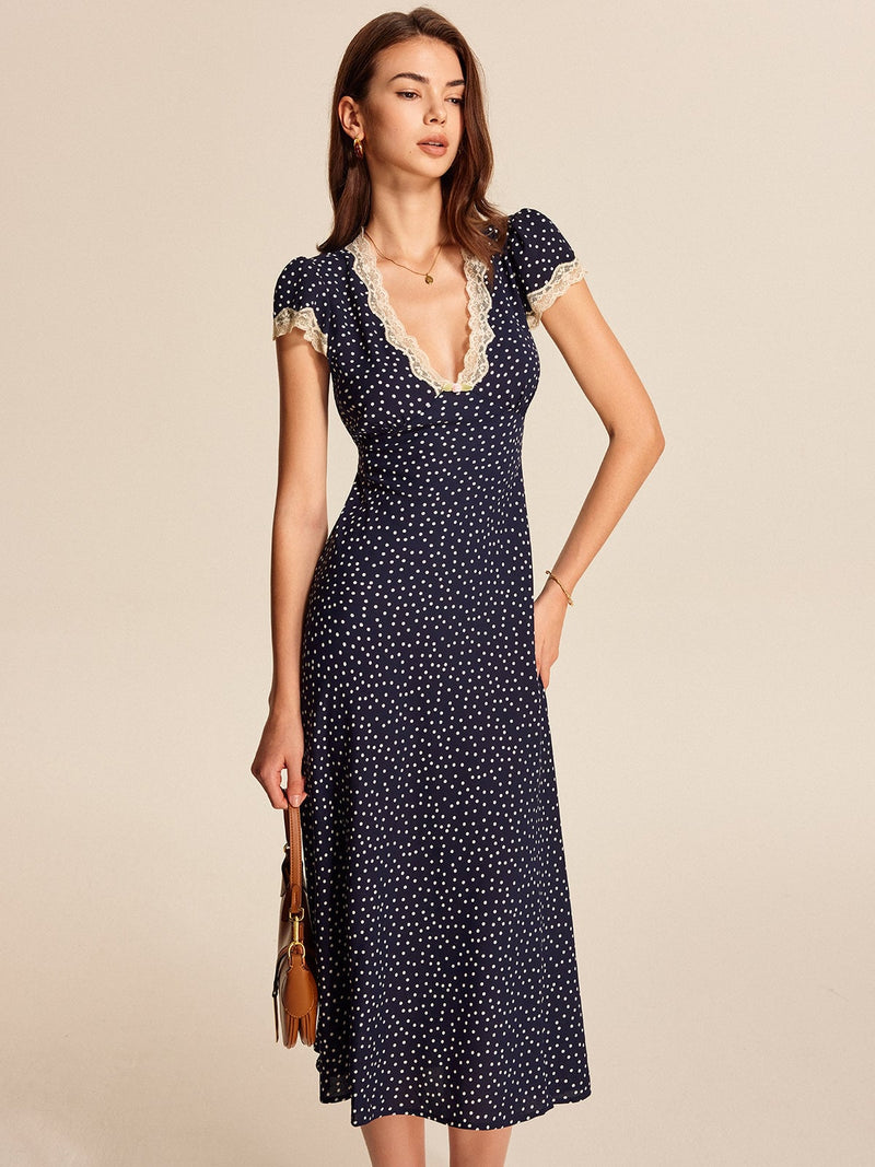 Close-up of delicate cream lace trim detail at the V-neckline of a navy polka dot dress