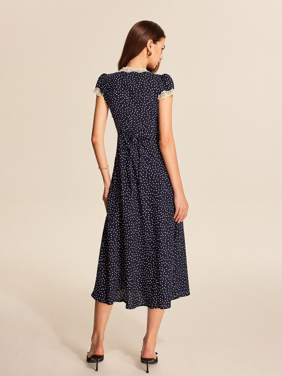 Detail shot of all-over polka dot print on deep navy fabric of the midi dress