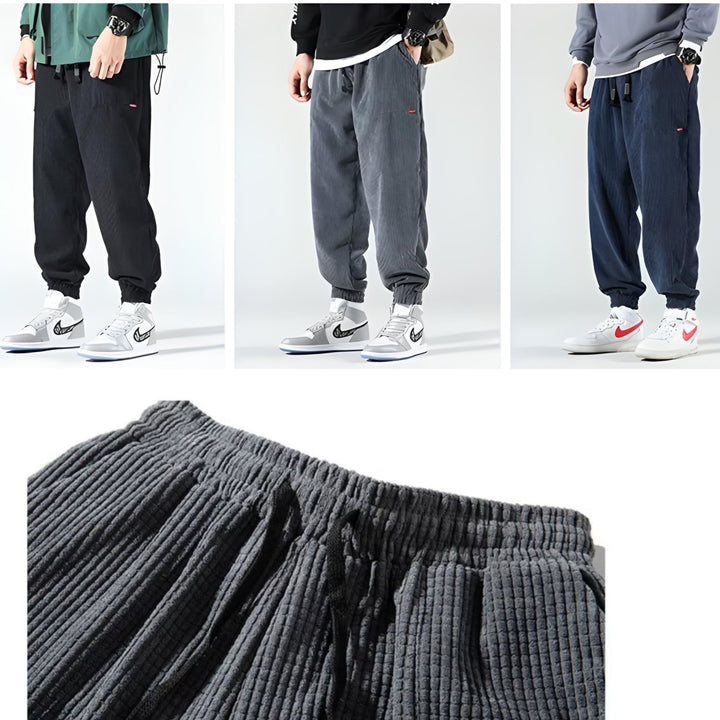 Flat lay of corduroy joggers in marine blue, grey, and black showing all available color options