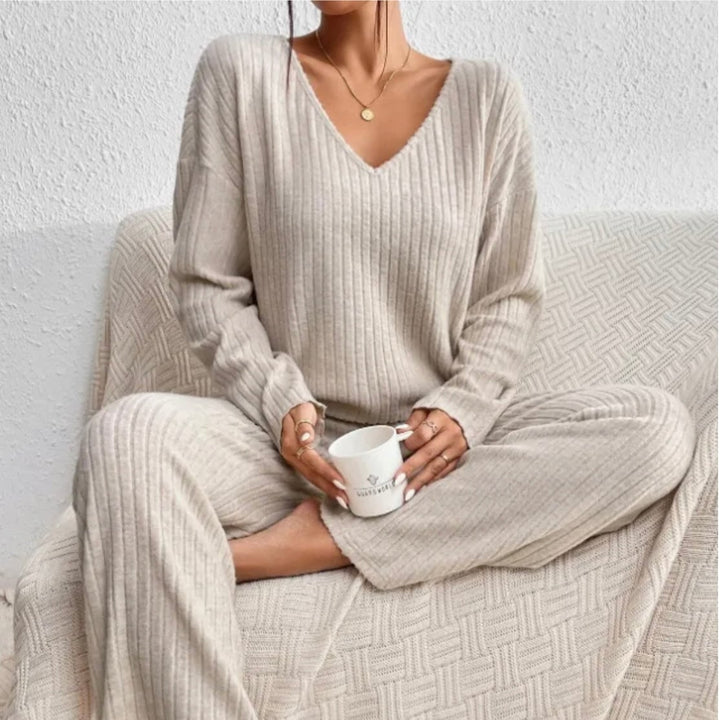 Woman wearing a ribbed knit two-piece sweater and trouser set in beige with a V-neckline