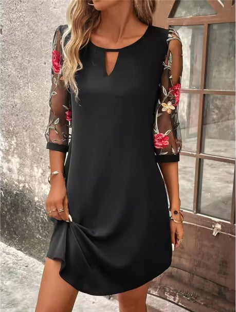Woman wearing a black floral V-neckline dress with sheer long sleeves, front view