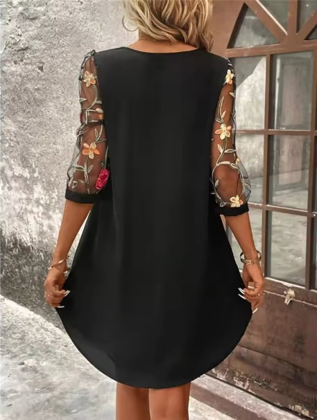 Close-up detail of sheer statement sleeves on a black floral V-neckline dress