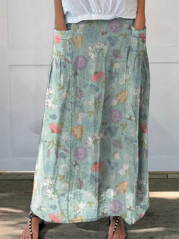 Green A-line skirt with floral and bumble bee print, elastic waistband, and side pockets, shown in full length