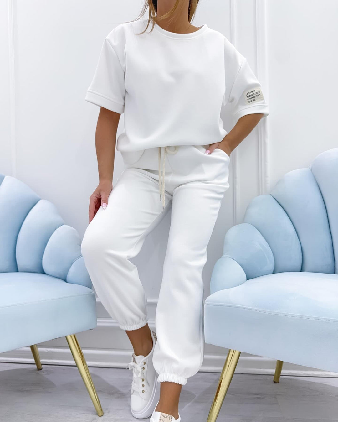Woman wearing a white short sleeve matching set with relaxed fit top and coordinating trousers