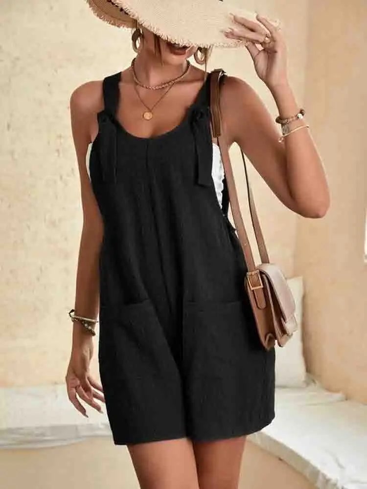 Side view of the Daisy linen romper in black highlighting the front patch pockets and loose silhouette