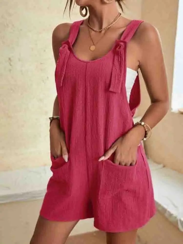 Close-up of the adjustable tie-strap shoulders and scoop neckline on the Daisy linen romper in pink