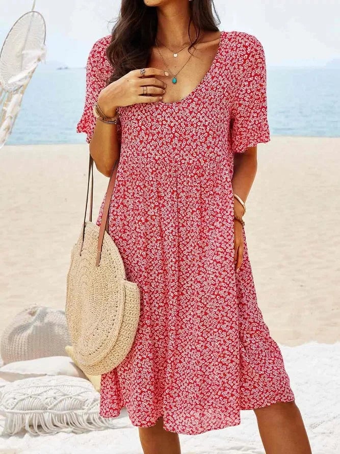Front view of a ditsy floral smock dress showing the V-neckline button detail and smocked empire waist