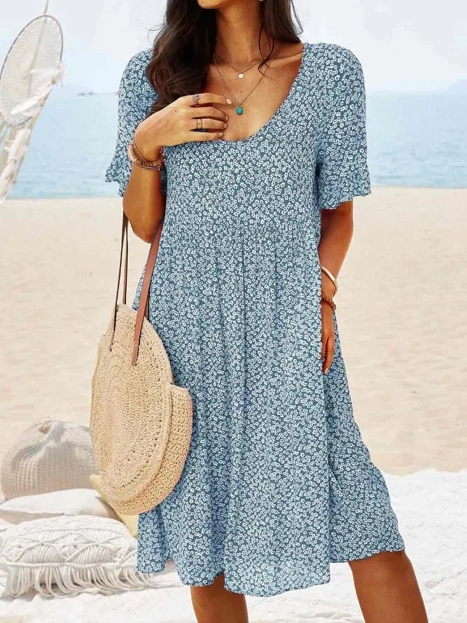 Model wearing the floral smock dress in red colorway styled with sandals for a summer look