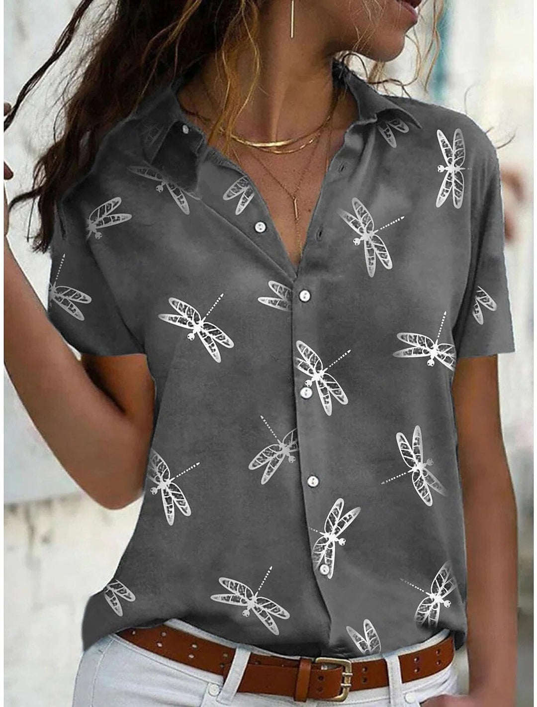 Model wearing the Daisy dragonfly print shirt in green with light-wash denim jeans