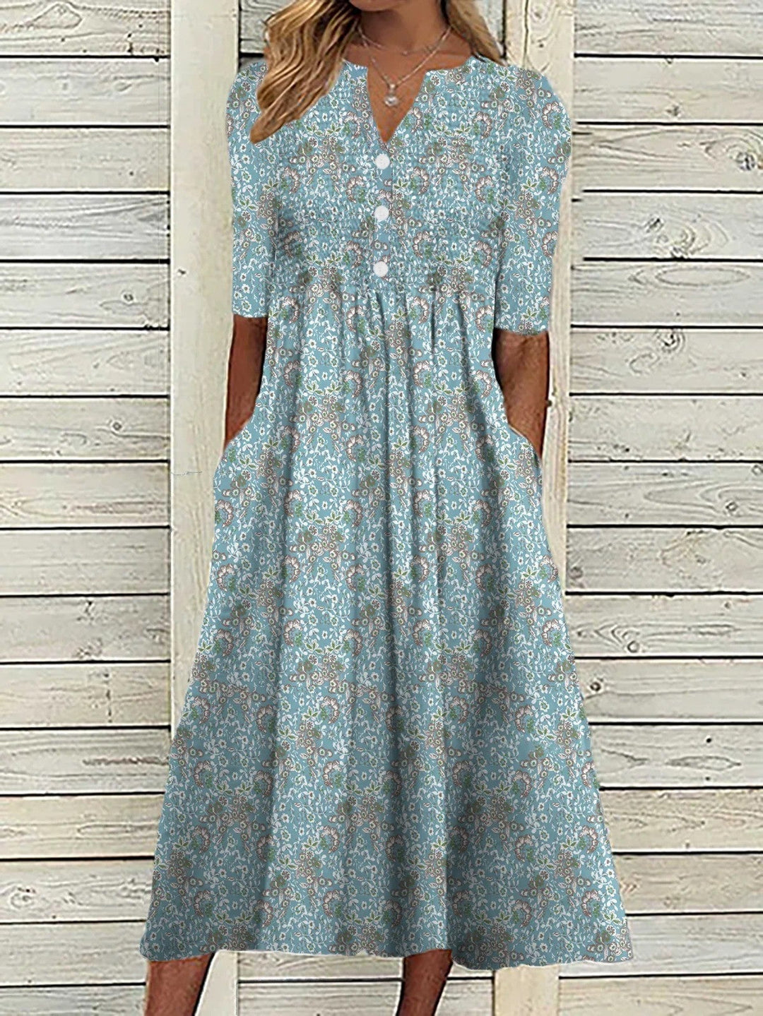 Woman wearing a blue floral print v-neck midi swing dress with gathered waist and half sleeves