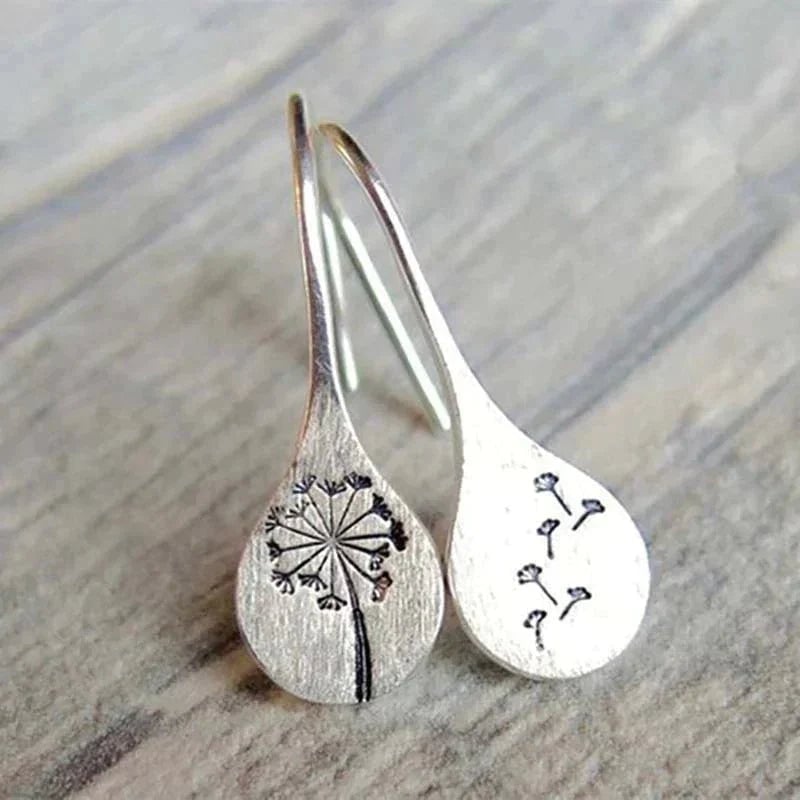Close-up of sterling silver dandelion earrings with delicate petal detail on a neutral background