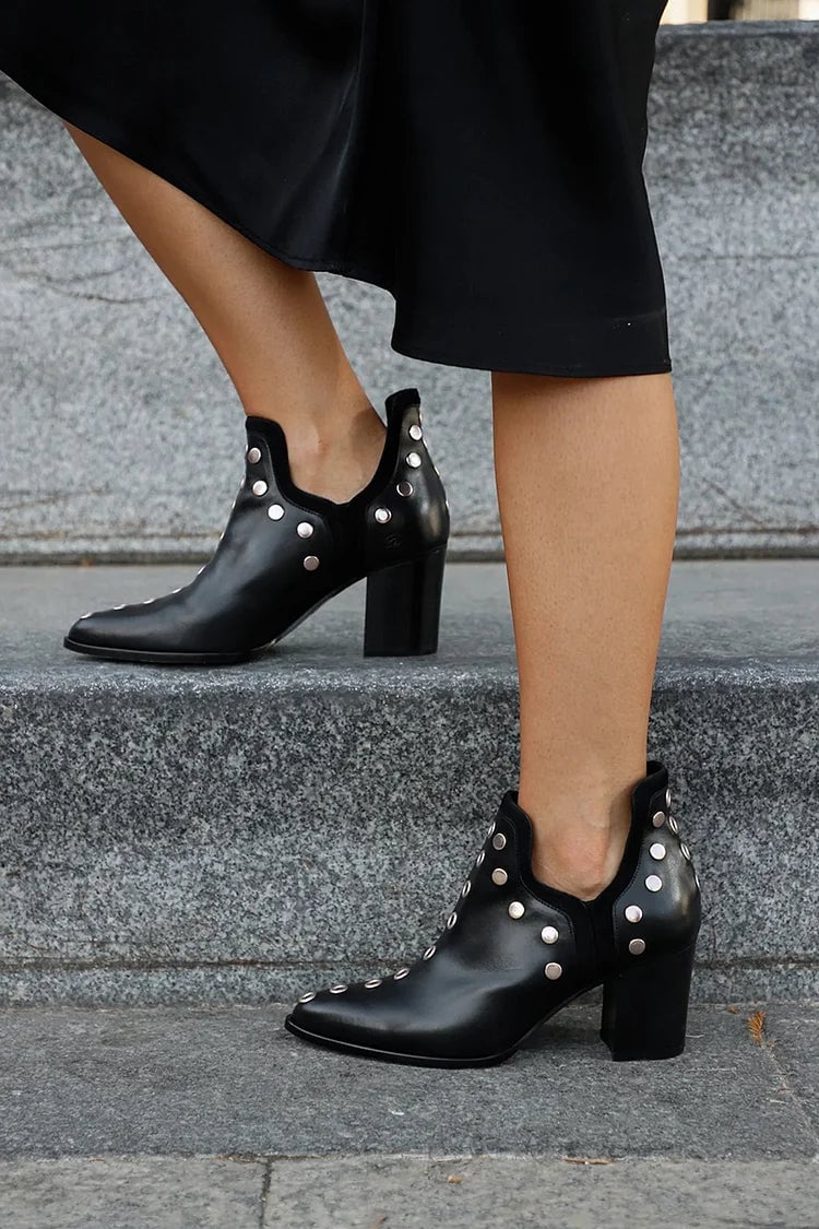 Close-up of metallic stud accents on black wide-heel boots showing bold edgy detail