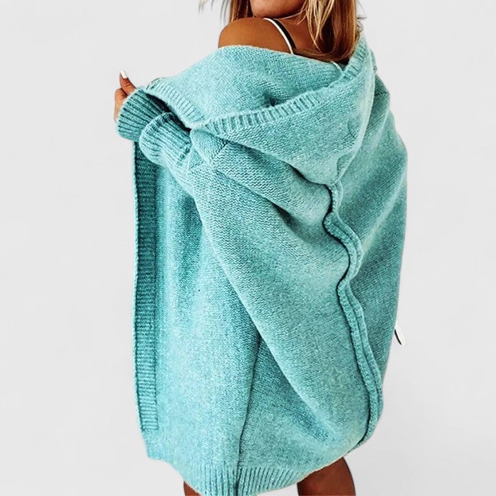 Woman wearing a relaxed oversized hooded knit cardigan in blue with knee-length silhouette, front view