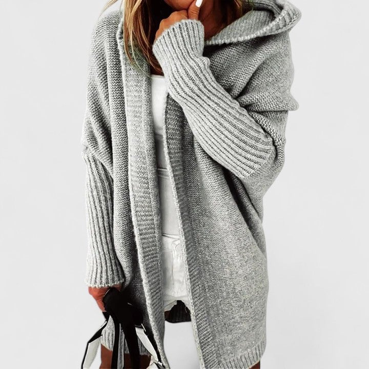 Woman in gray oversized hooded knit cardigan styled with jeans, side profile view