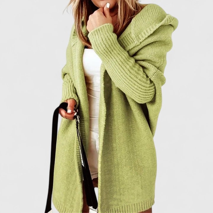 Woman wearing a green oversized hooded knit cardigan, back view showing hood detail