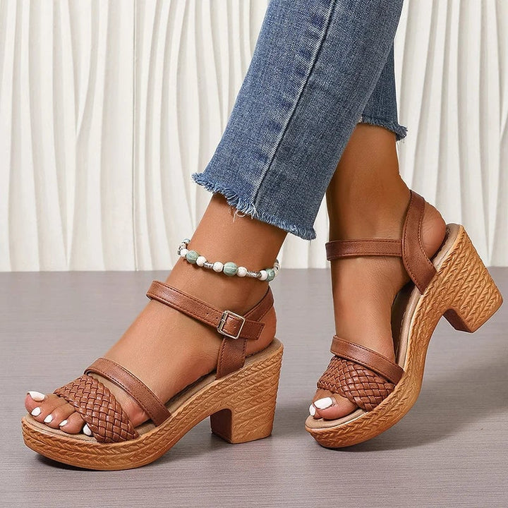 Black woven platform sandals close-up showing the adjustable ankle buckle strap