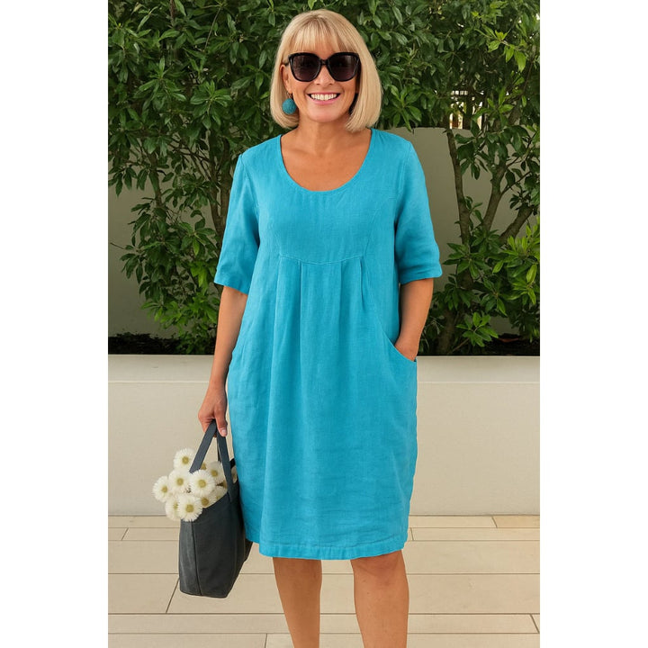 Woman wearing a light airy pleated summer comfort dress in blue with a relaxed flattering fit