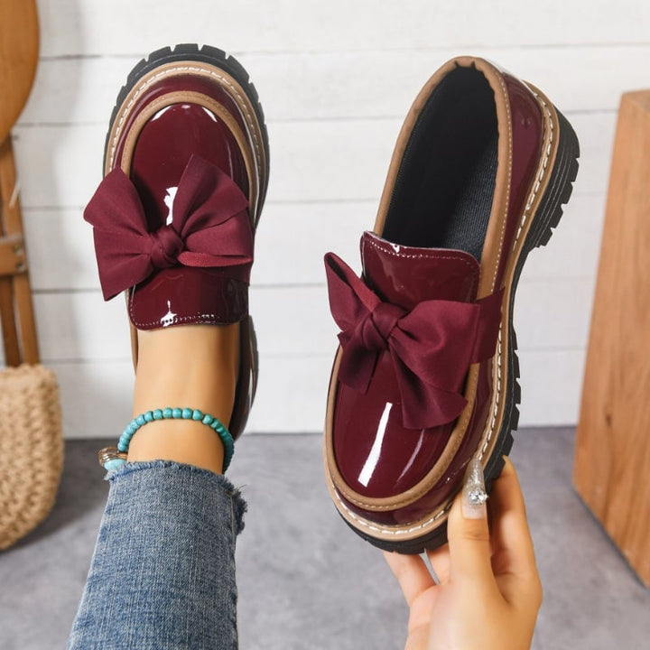 Overhead flat-lay of Demi bow loafers in brown showing the lug-style platform sole