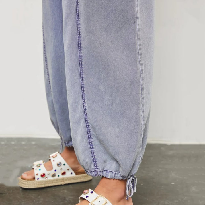 Front view of the Demi denim wide-leg jumpsuit in dark blue with smocked waist and side pockets