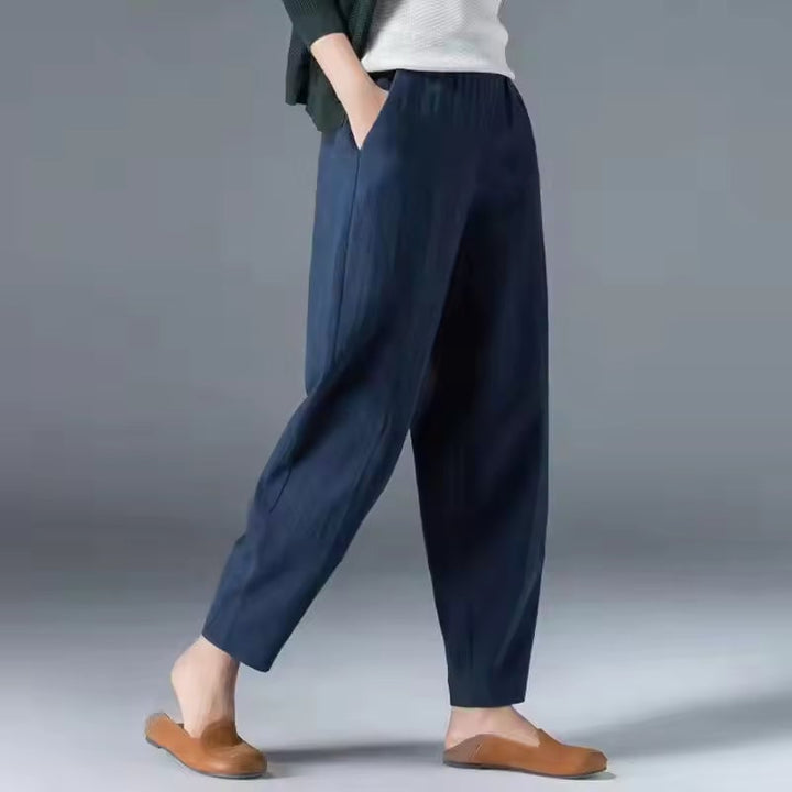Woman wearing beige lightweight summer trousers with a relaxed ankle-length silhouette and elastic waistband