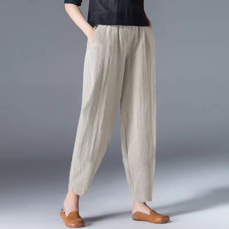 Woman in yellow breezy summer trousers paired with a white tank top on a sunny day
