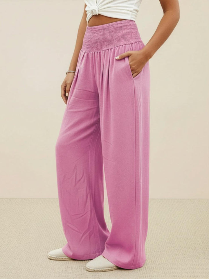 Model styled in light pink wide leg pants with a tucked-in blouse