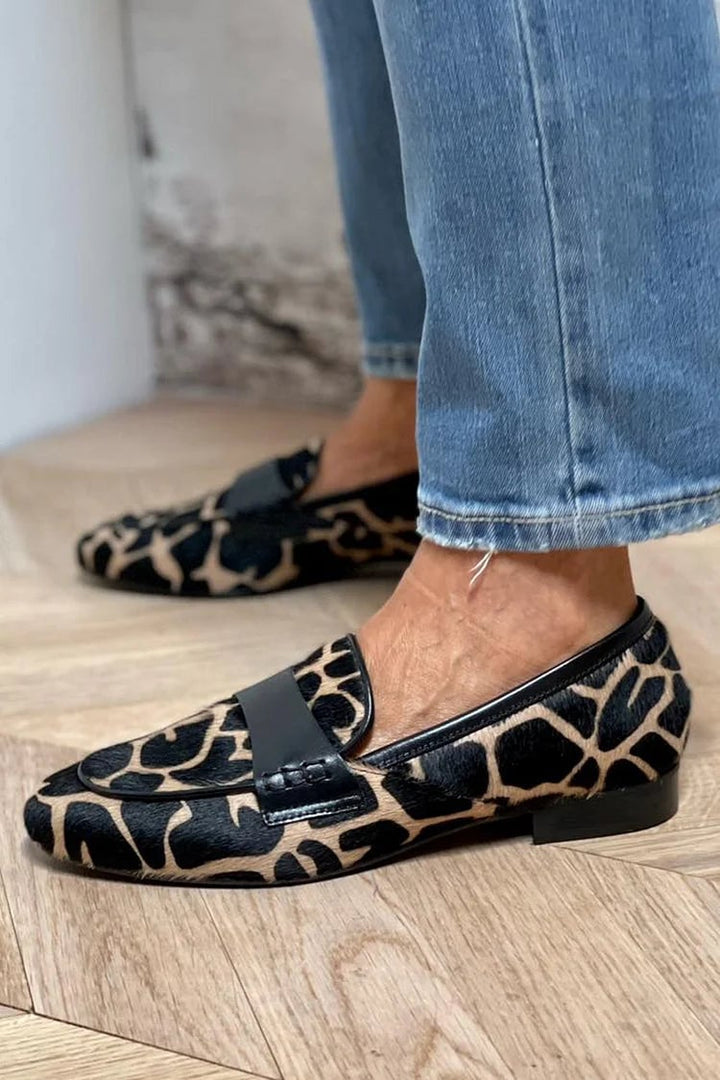 Close-up side view of black animal print loafers with a sleek, flattering silhouette on a light background
