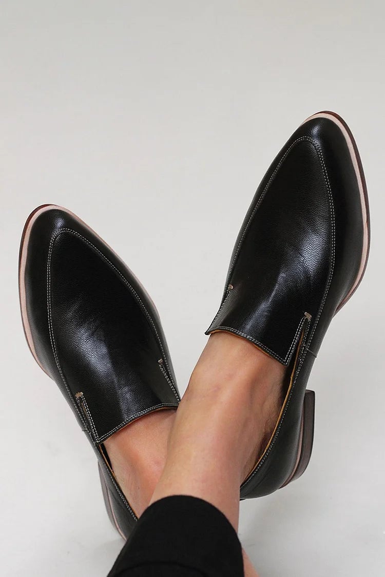 Side view of black minimalist loafers with a clean streamlined silhouette on a neutral background