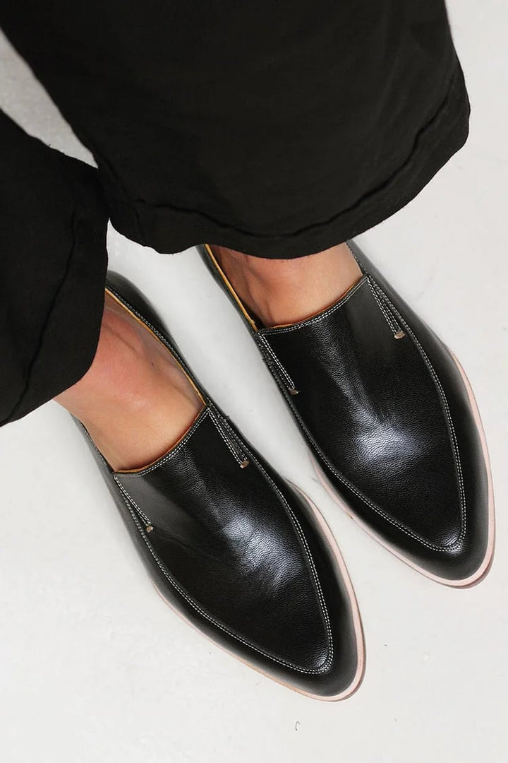 Front angle close-up of black minimalist loafers showing sleek toe and soft upper construction