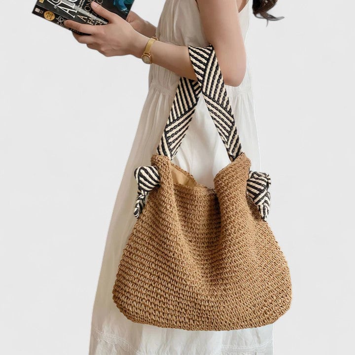 Warm brown bohemian braided shoulder bag with patterned straps on a neutral background
