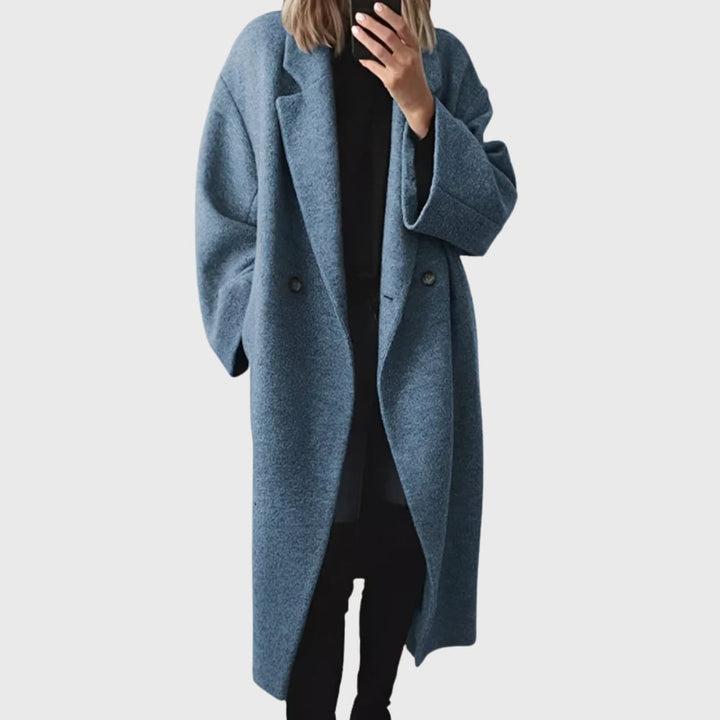 Woman styled in the Elda longline overcoat paired with trousers, showcasing its elongating silhouette