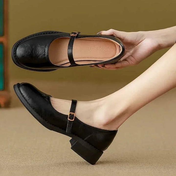 Close-up of Eleanor mary jane shoe buckle strap detail in brown leather-look finish