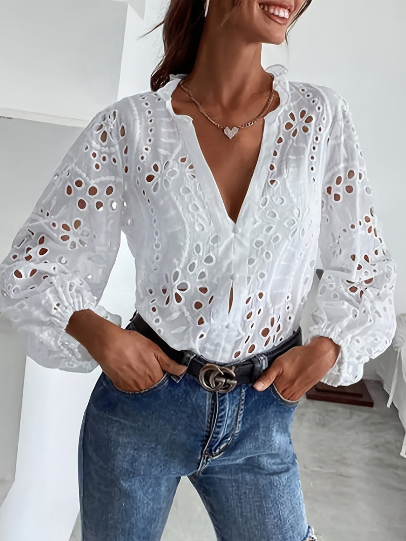 Close-up of intricate embroidery and openwork design on a white long-sleeve blouse