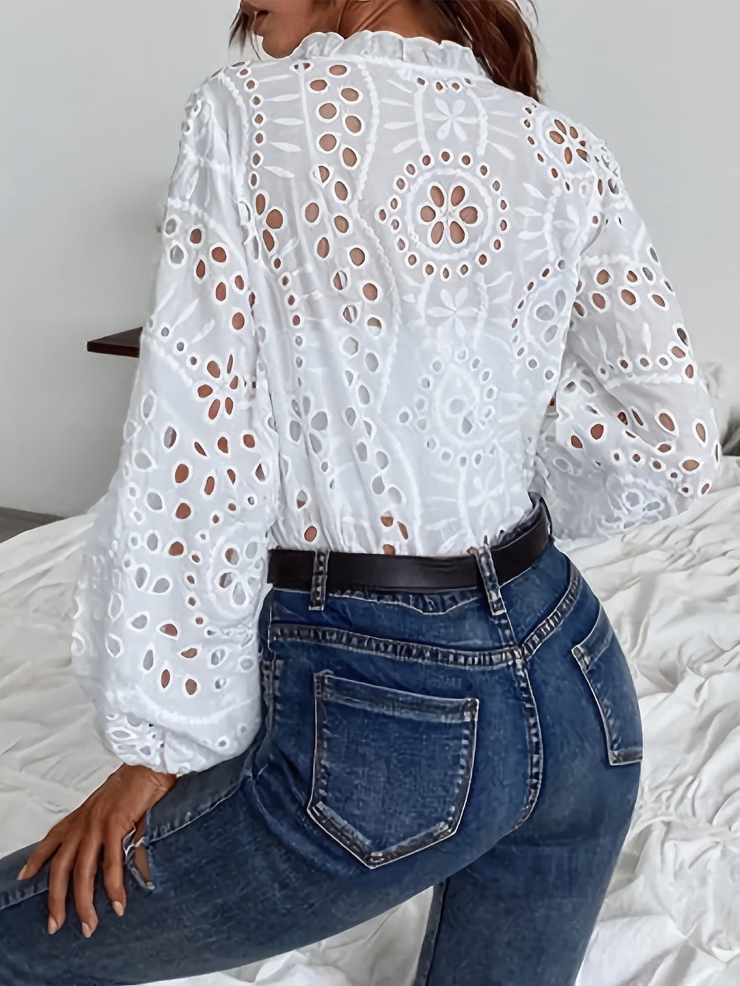 Model wearing a white embroidered floral blouse with elegant long sleeves, styled casually