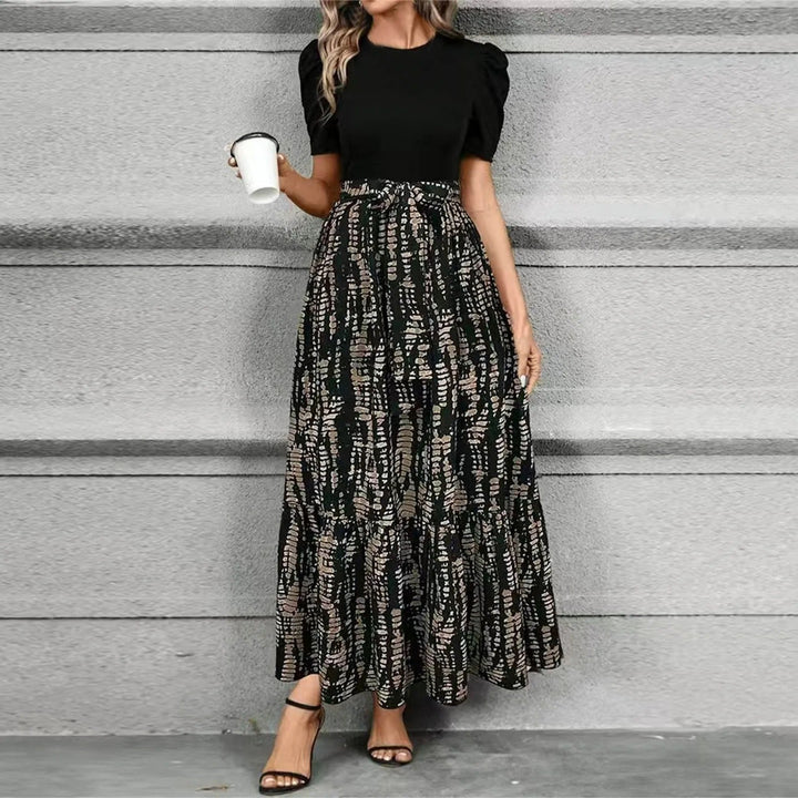 Close-up of the Elise maxi dress showing the bold botanical-print skirt and tiered ruffle hem detail