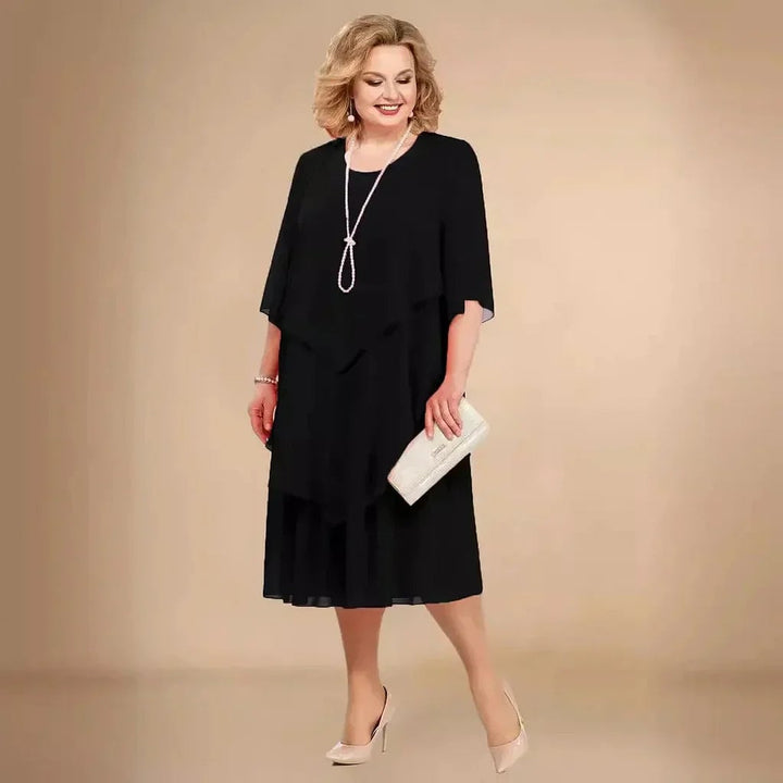 Model wearing the Ellen elegant chiffon dress in black, showing flowing layers and knee-length silhouette