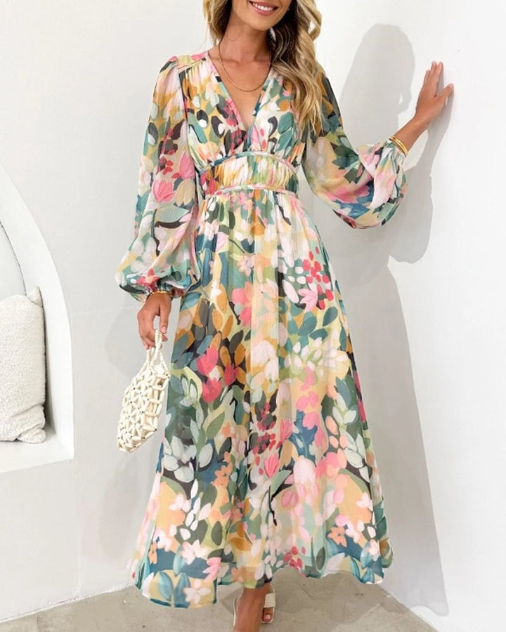 Back view of the Eloise floral midi dress showing the gathered long sleeves with cuffed hem and full A-line silhouette in blush, sage, and peach print
