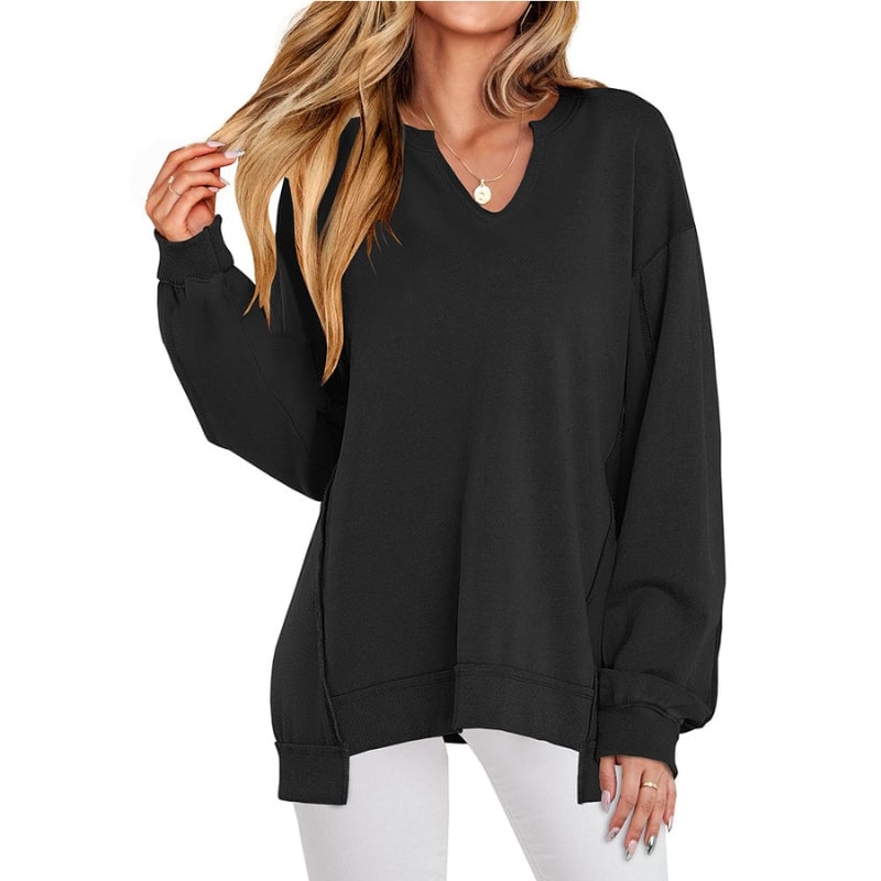 Woman wearing an oversized V-neck sweatshirt tunic in black with ribbed cuffs and a relaxed dropped-shoulder fit