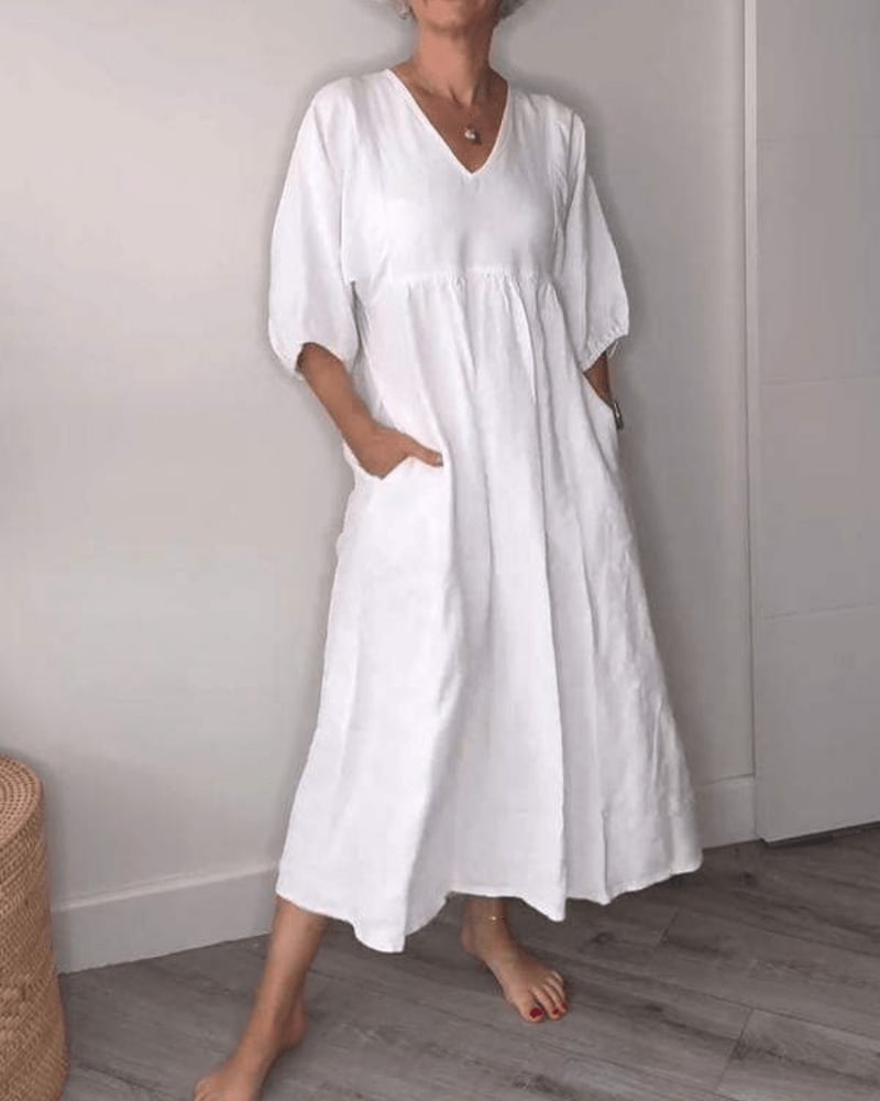 Woman wearing a flowing white V-neck maxi dress with an elegant silhouette, front view