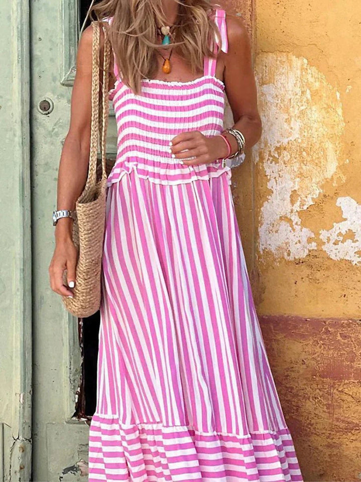 Front view of the Emilia striped dress in pink with tailored bodice and flowy skirt on a female model