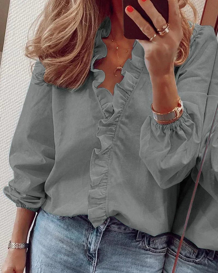 Woman wearing a black ruffle neckline blouse with balloon sleeves styled for an evening occasion
