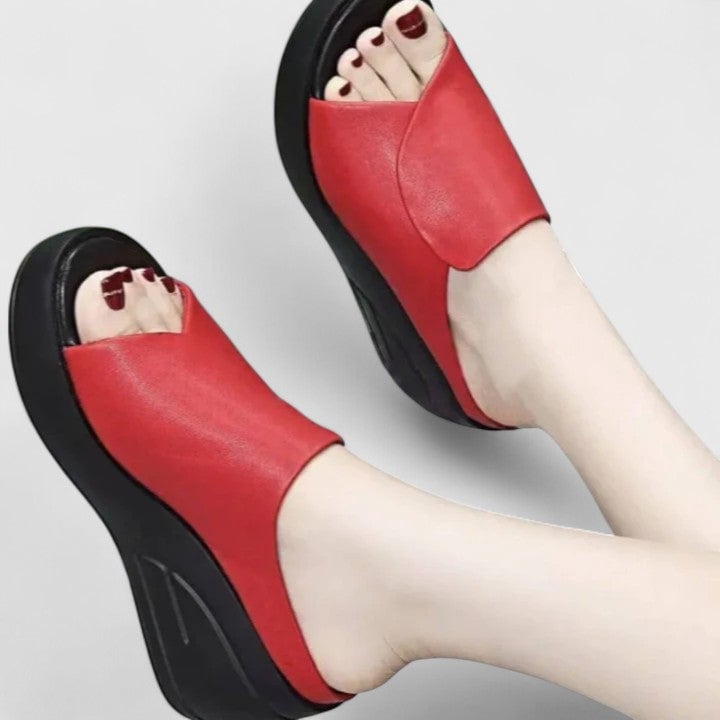 Woman stepping forward in black orthopedic wedge sandals, showcasing alignment support and elevated heel