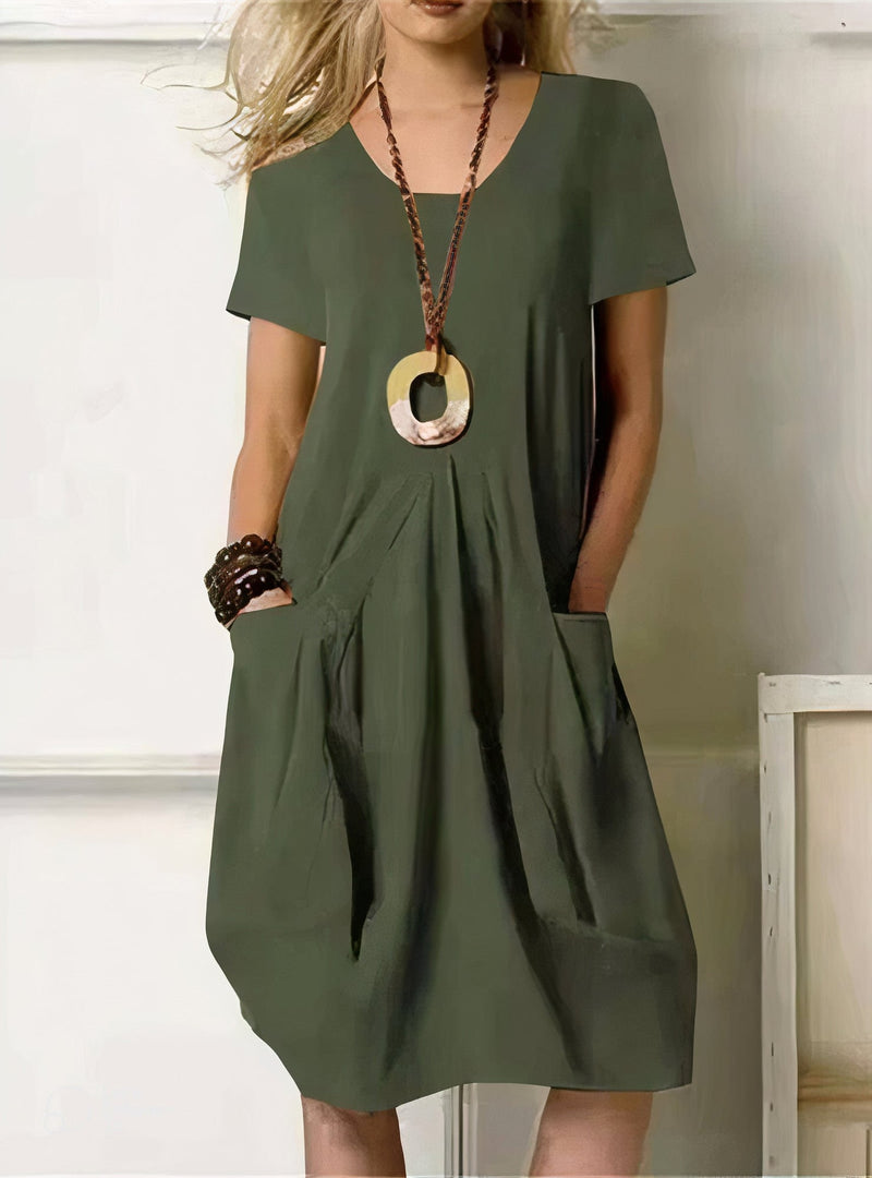 Woman wearing the Evelyn relaxed fit dress in orange, standing in a bright outdoor setting