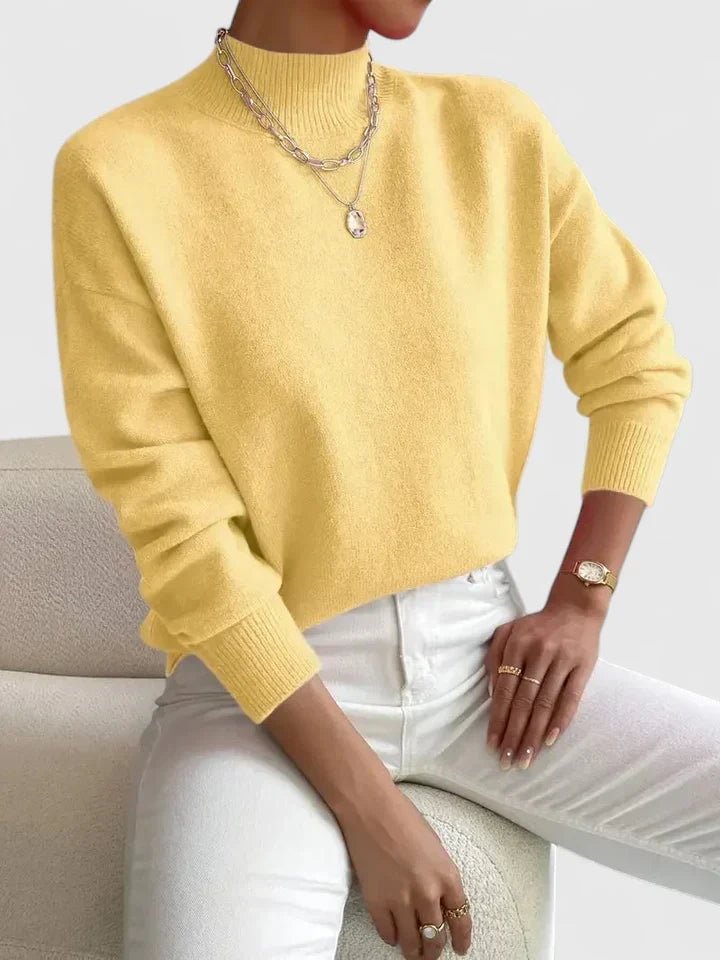 Model in a light pink Evelyn turtleneck sweater paired with high-waisted trousers
