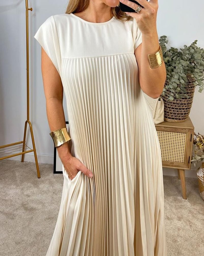 Woman wearing the Fern flowy pleated maxi dress in beige, showcasing the full-length silhouette